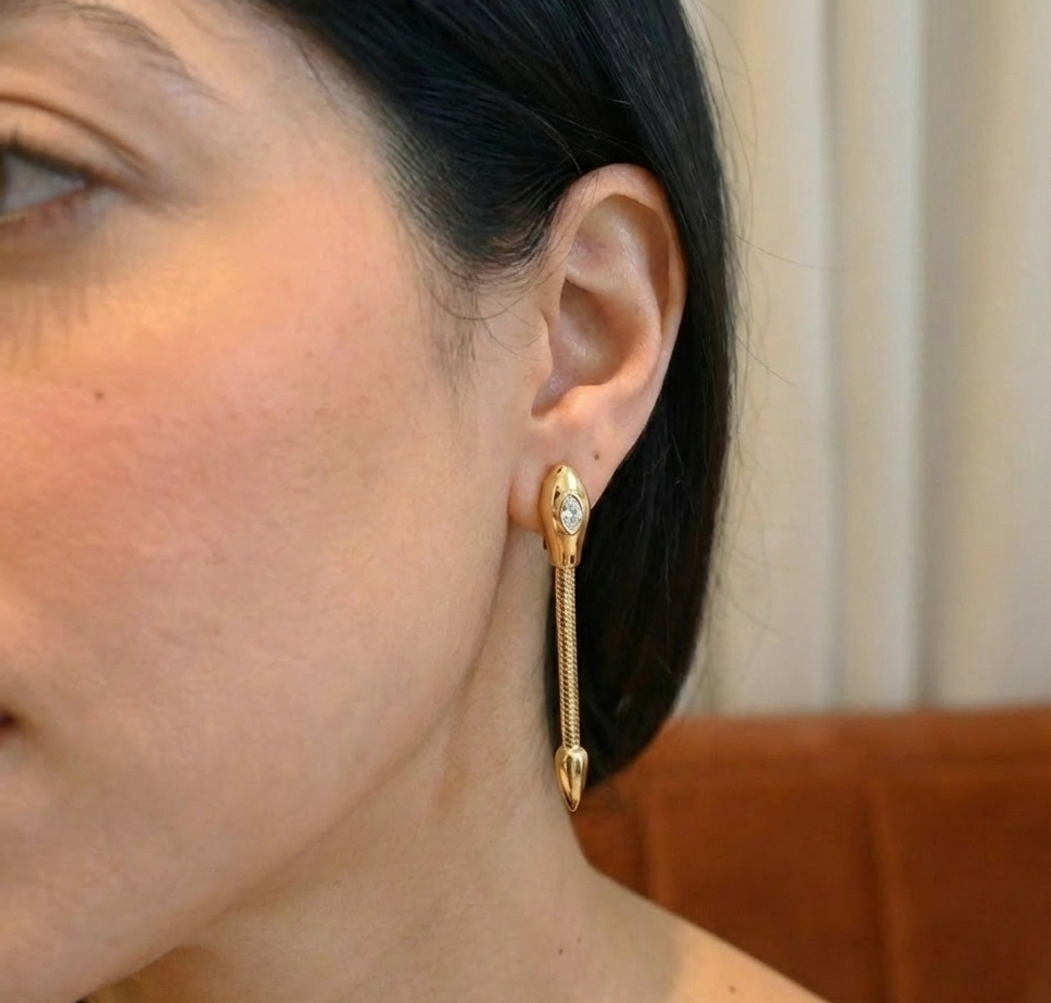 Close-up of a person wearing a gold earring with a diamond, set against a neutral background.