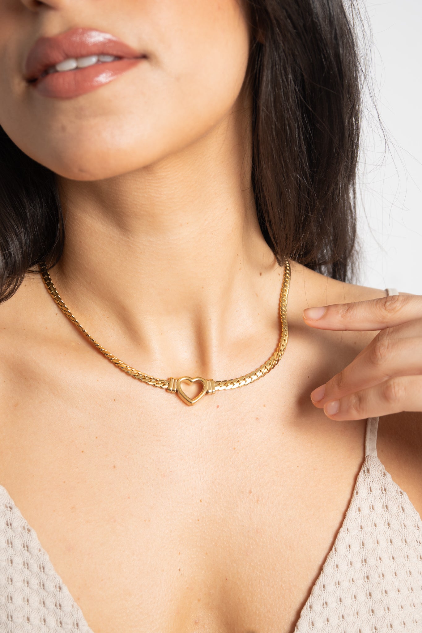 Close-up of a woman wearing a gold necklace with a heart pendant.