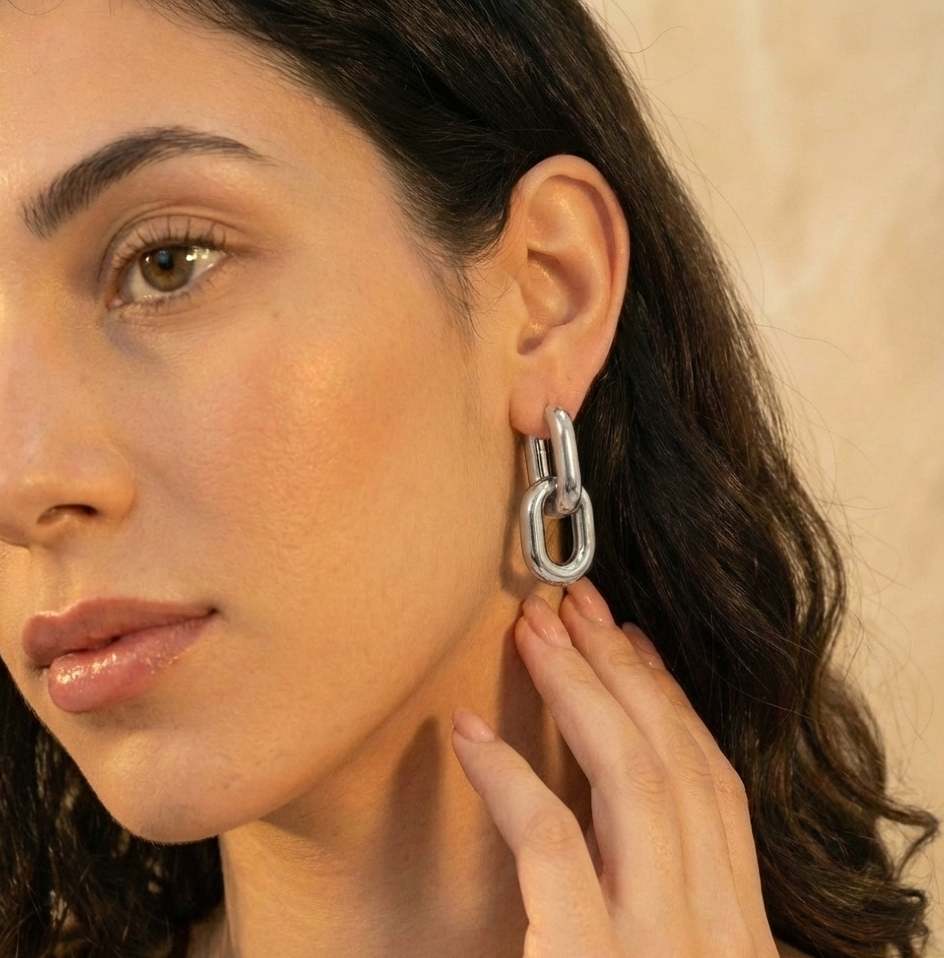 Close-up of a woman wearing a silver earring against a neutral background