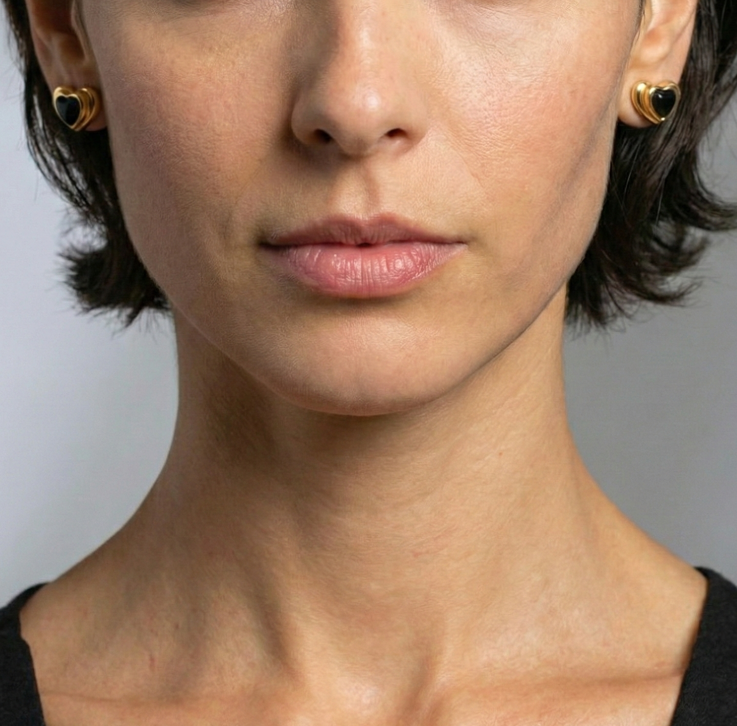 Close-up of a woman wearing gold earrings against a gray background