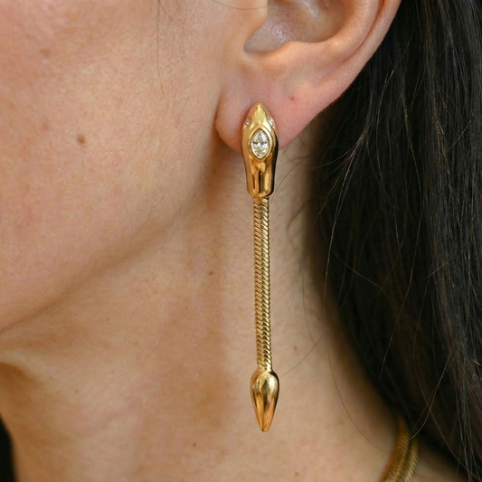 Gold earring with a snake design worn by a person