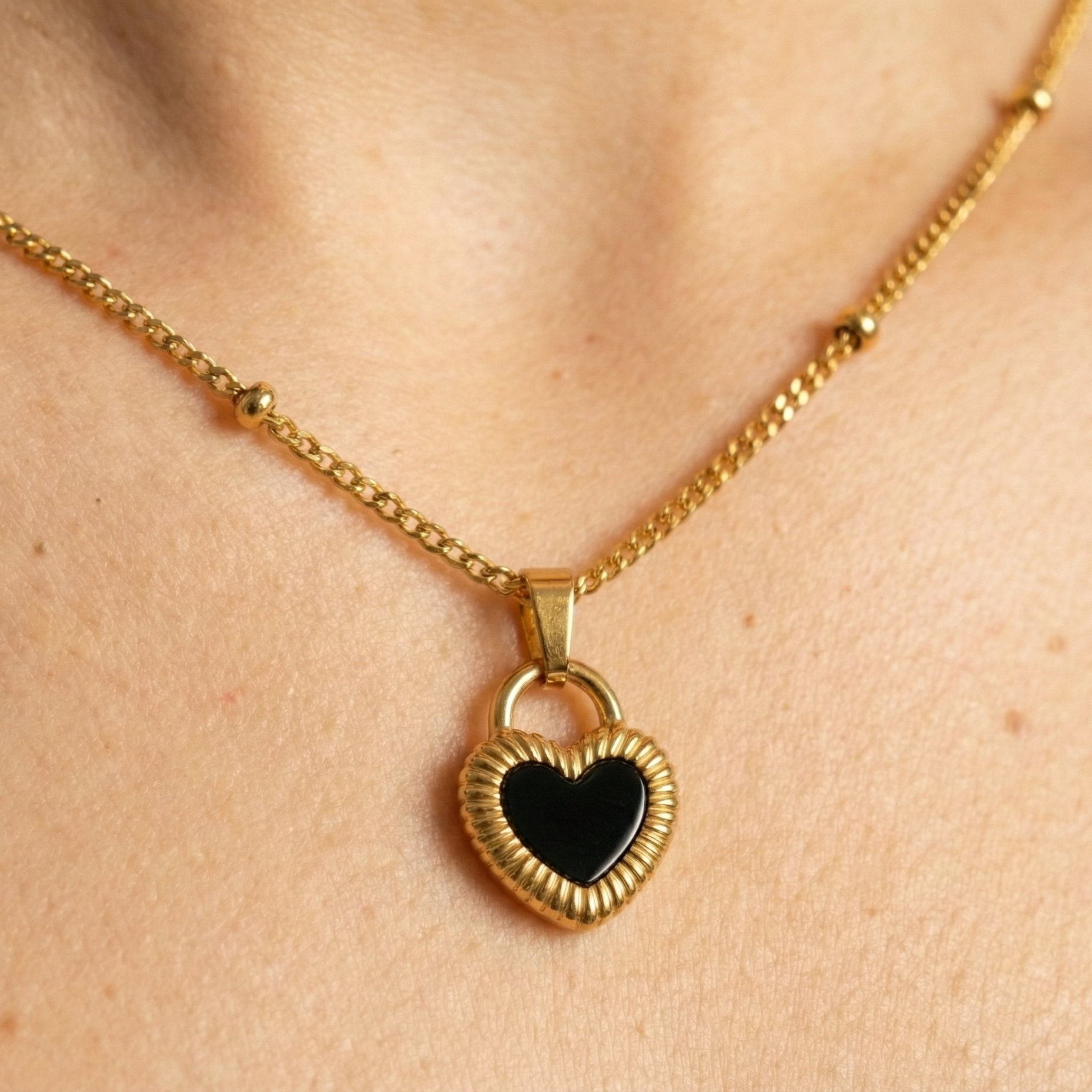Gold necklace with a heart-shaped pendant on a person's neck