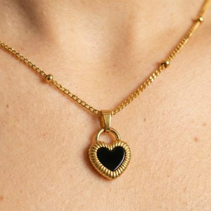 Gold necklace with a heart-shaped pendant on a person's neck