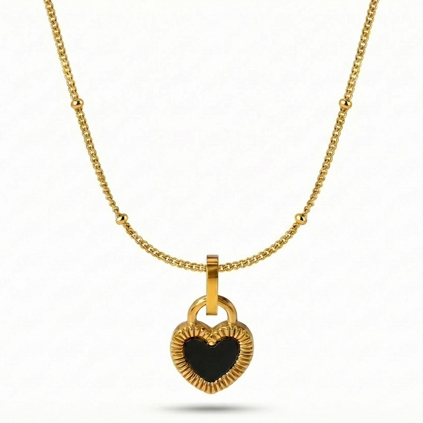 Gold necklace with a heart-shaped pendant on a white background