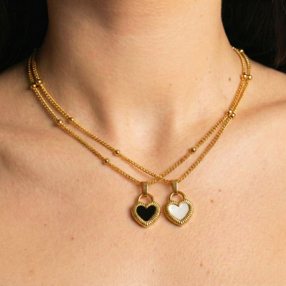 Gold necklaces with heart-shaped pendants on a person's neck