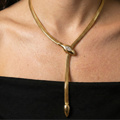 Gold snake-shaped necklace on a person wearing a black top
