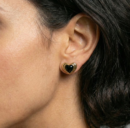 Heart-shaped earring worn by a person with dark hair.