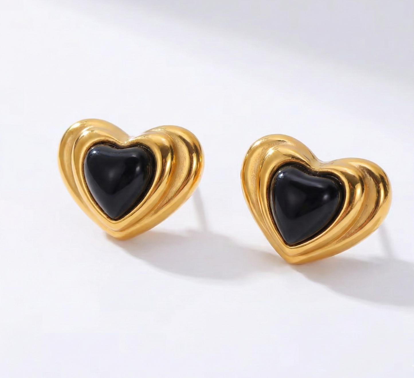 Heart-shaped earrings with gold and black design on a white background