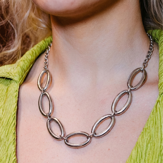 Necklace with large oval links worn by a person in a green top