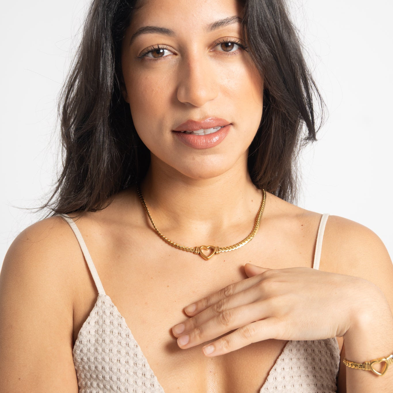 Woman wearing a gold necklace and bracelet against a white background