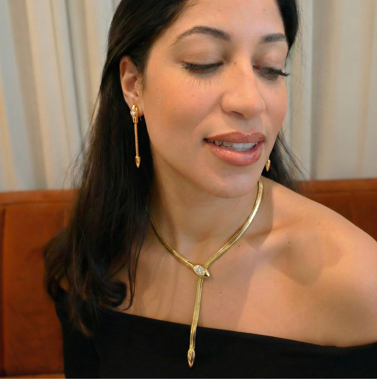 Woman wearing a gold necklace and earrings with a blurred background