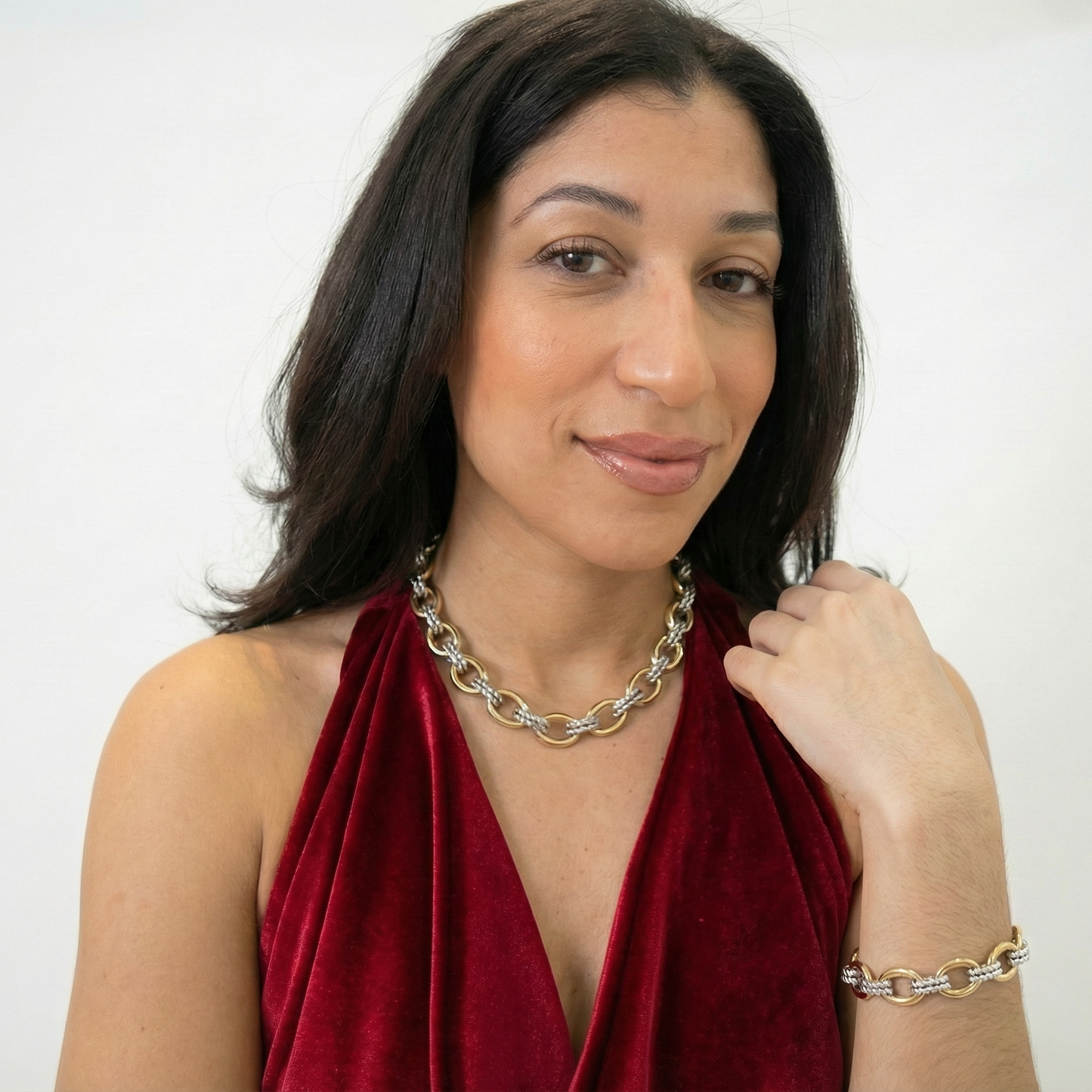 Woman wearing a red top and silver chain necklace against a white background