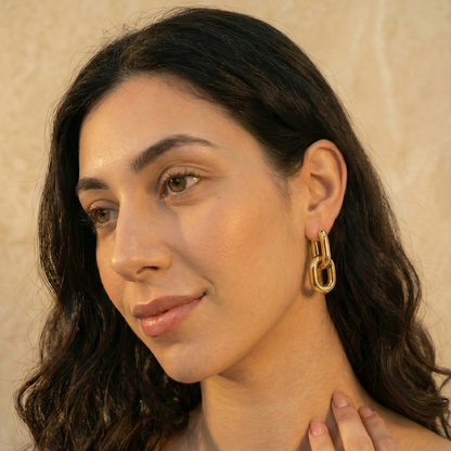 Woman wearing gold hoop earrings with a neutral background